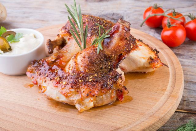 freshly cooked chicken breast artfully garnished and displayed on a wooden tray